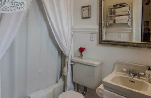 Bathroom with white walls, cream toilet, cream sink, cream bathtub, and white curtains