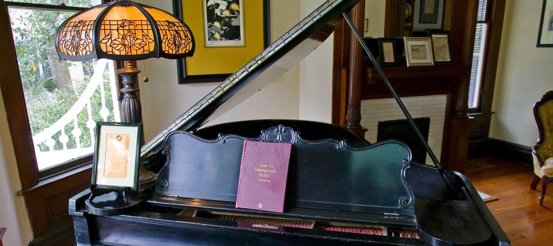 Old black piano with red-covered book and antique lamp